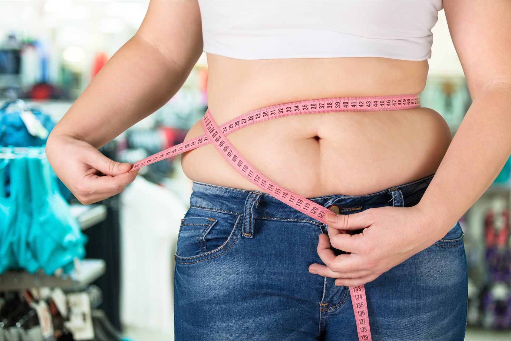 Bauch einer Frau, um den ein Maßband gewickelt ist