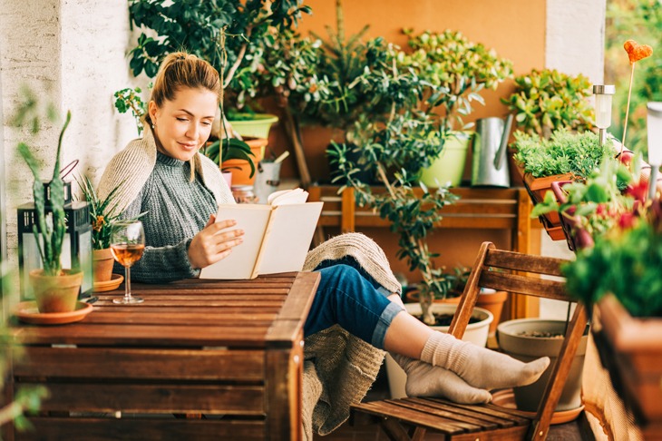 Ein Frau sitzt auf einem Balkon und liest ein Buch